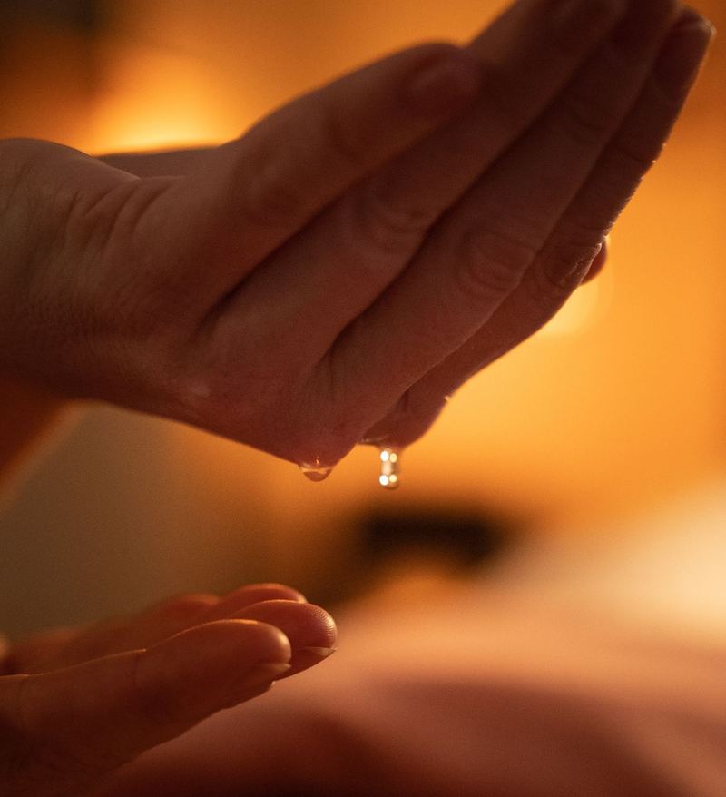 Olie druppelt traag van een hand, in warm tegenlicht