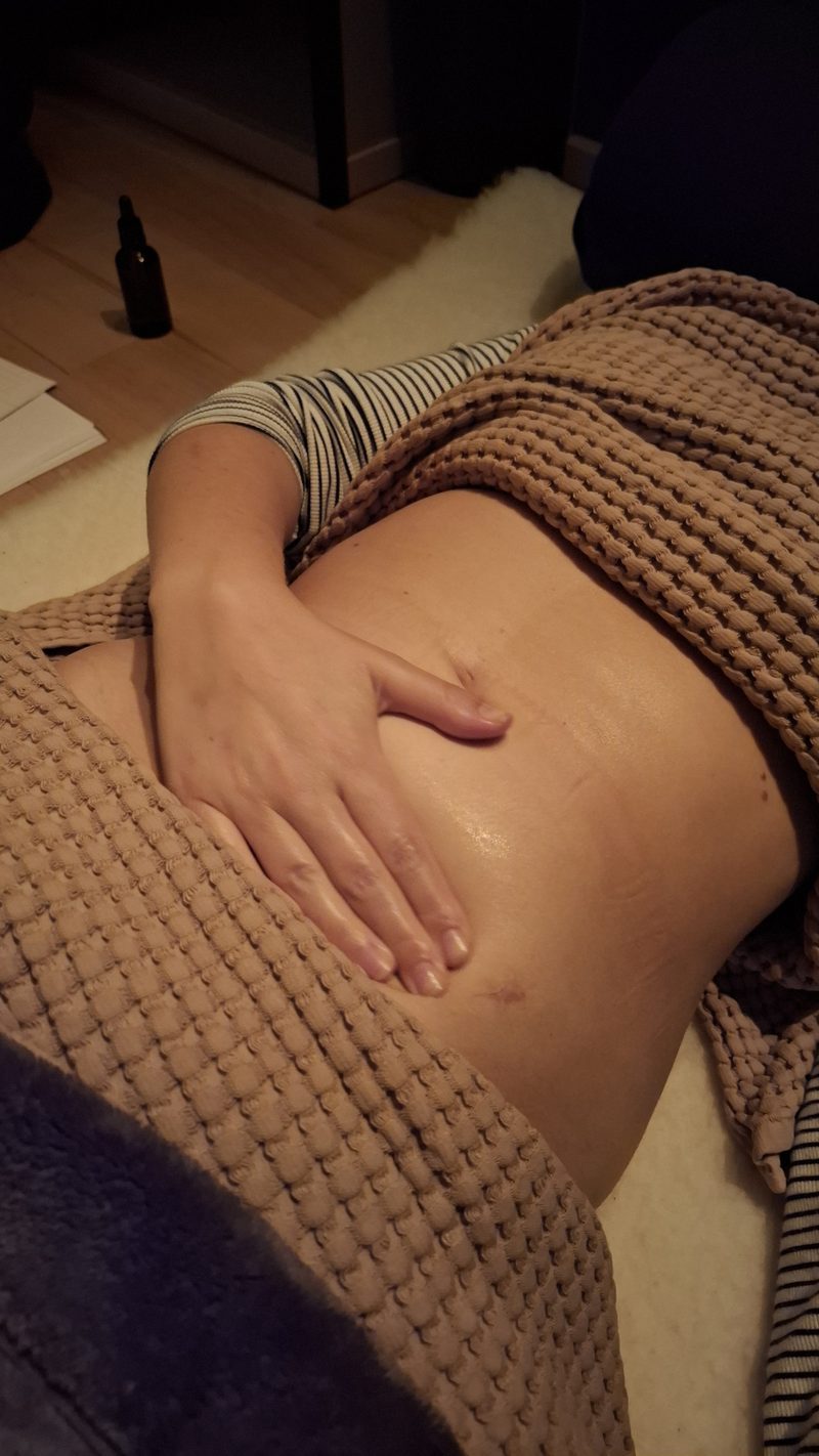 Een hand rust op een blote buik, half onder een warme deken