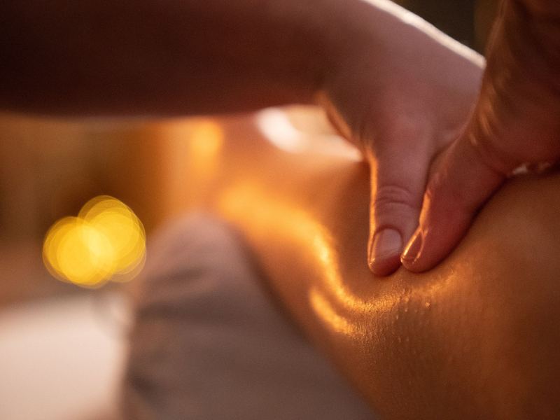 Twee handen rusten aandachtig op een schouder, in warm kaarslicht