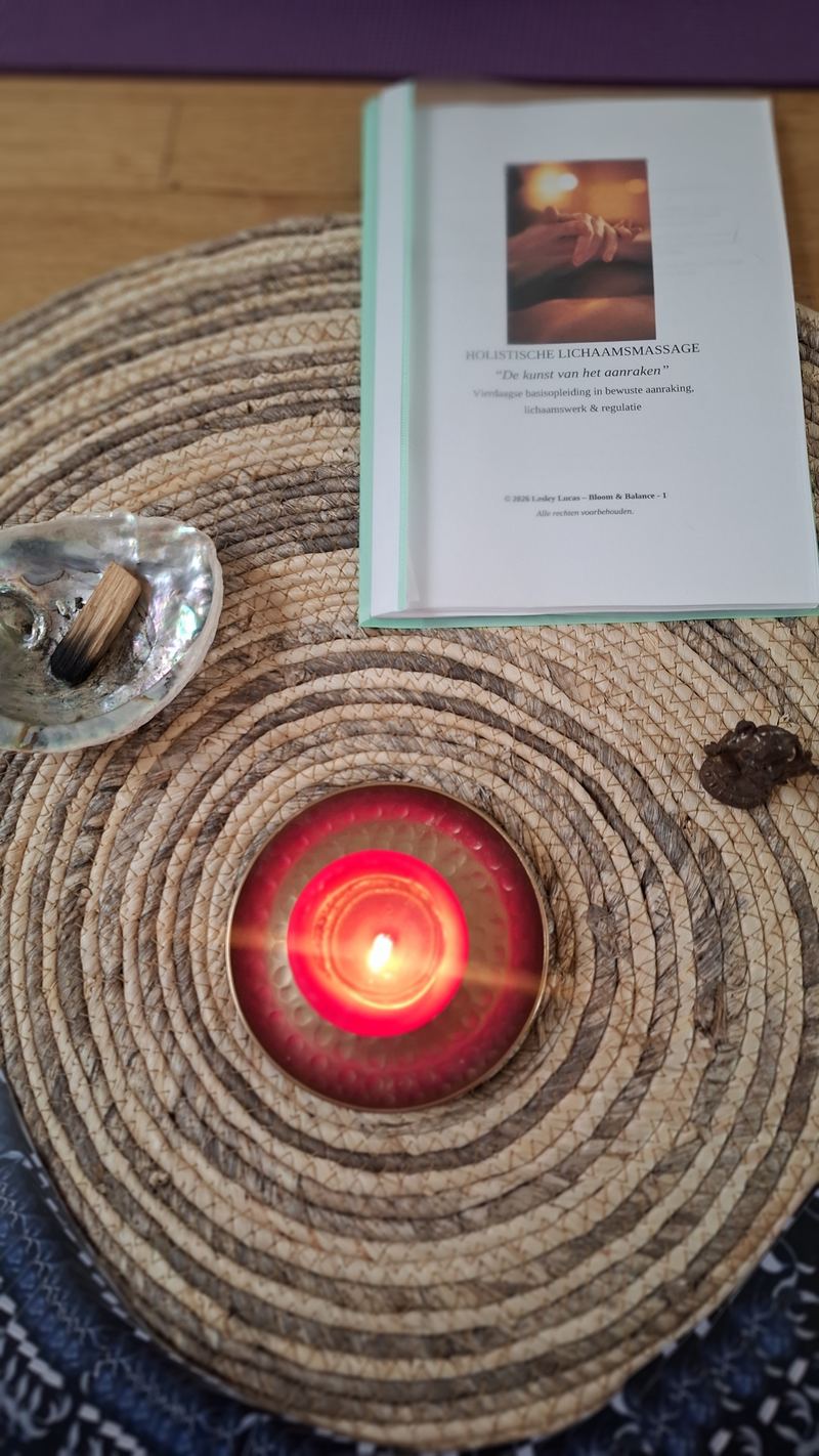 Een cursusboek naast een brandende kaars op een geweven mat