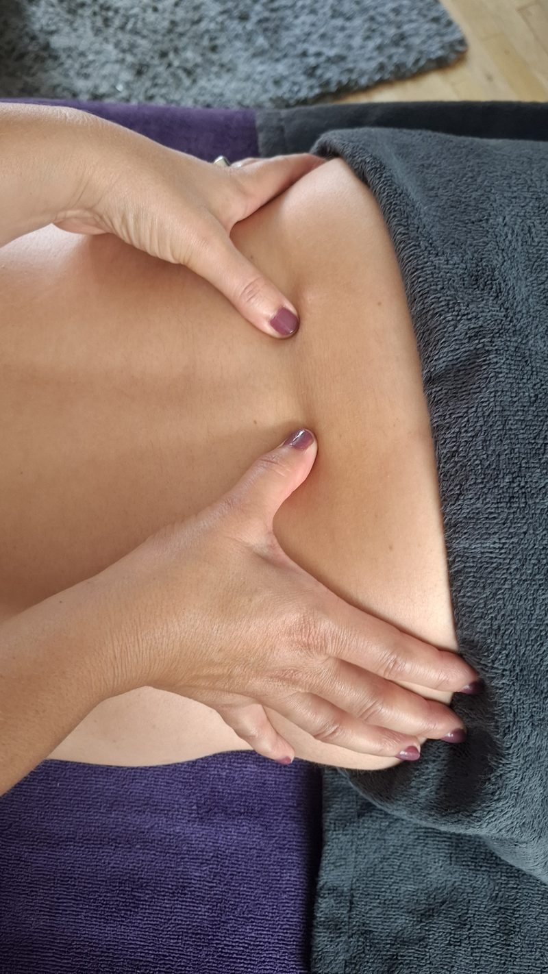 Twee handen masseren aandachtig een bovenbeen